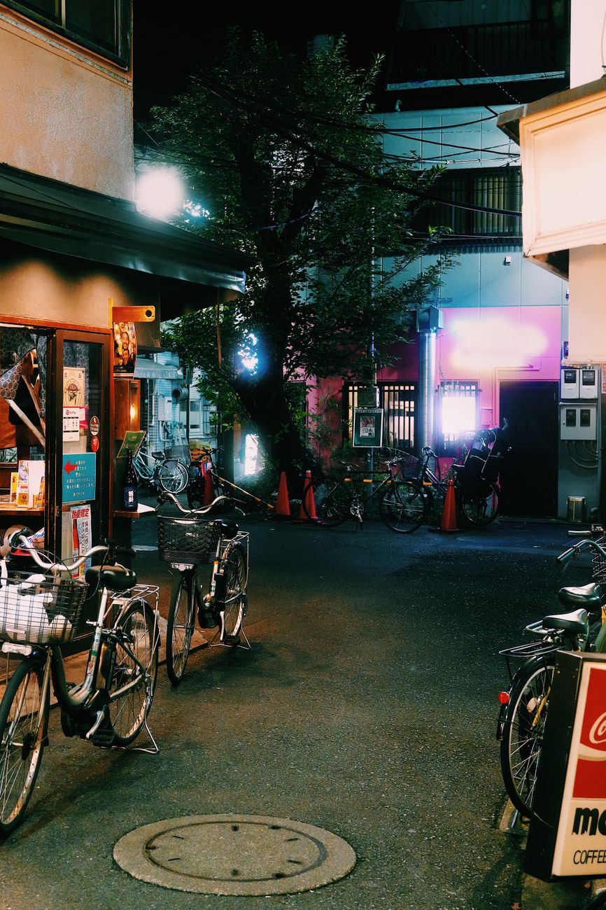 Vibrant Tokyo alley scene with neon lights and parked bicycles, capturing urban nightlife.