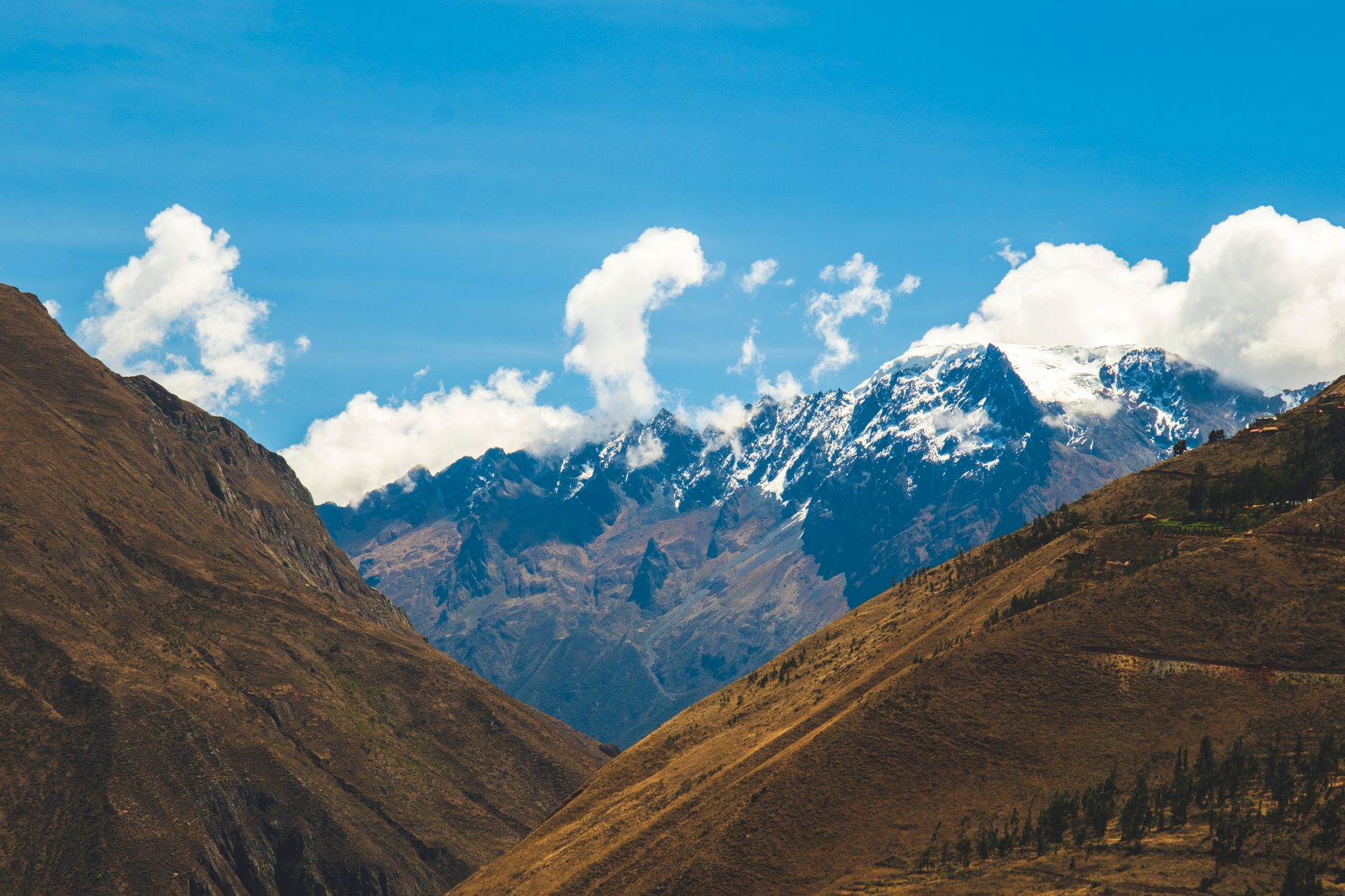 Breathtaking view of snow-capped Andes mountains under blue skies in Cusco, Peru.